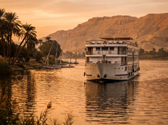 A Nile cruise ship passing palm-fringed banks at sunset