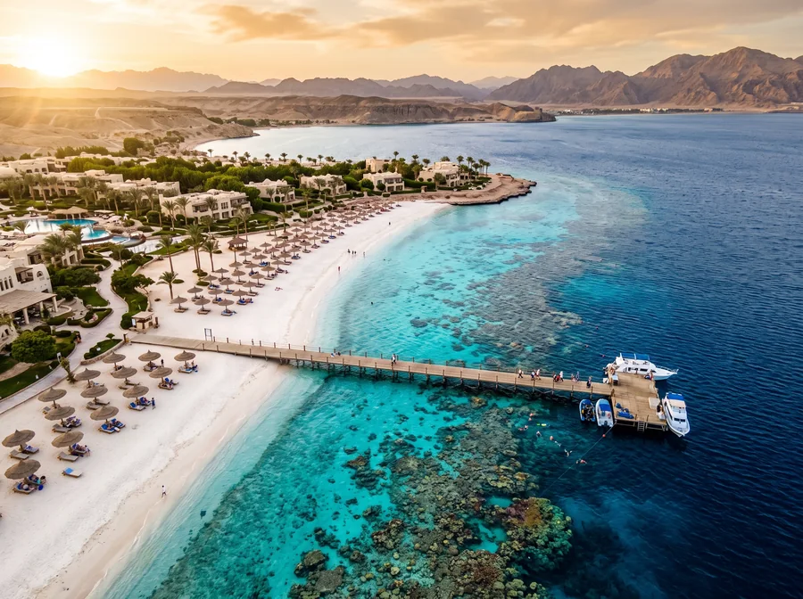 Turquoise water over a Red Sea coral reef beside a white sand beach